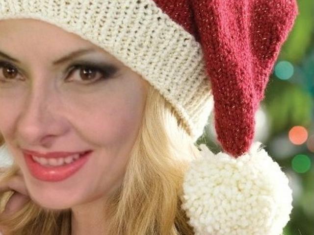 Leilys Gesicht mit blonden Haaren, einem roten Weihnachtsmannhut und einem weißen Pompon, lächelnd mit rotem Lippenstift, braunen Augen und einem leichten Teint, sieht süß und festlich aus..