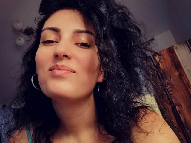 AddictedToUTS tiene el pelo negro y rizado, ojos marrones, y lleva aros grandes, con una ligera sonrisa en su rostro, mirando hacia abajo a la cámara. Sus senos no son visibles..