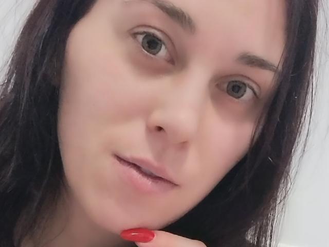 BlackberryGil ha la pelle chiara, i capelli castano scuro ed è rivolta verso la fotocamera con gli occhi grigi. Ha le unghie rosse ed è leggermente sorridente, con un dito vicino alla bocca..
