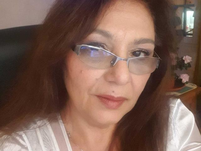 SxyVivian has brown hair, glasses, and a small nose piercing, wearing a white shirt. Her ass is not visible. Her pussy is not visible. Her tits are not visible.