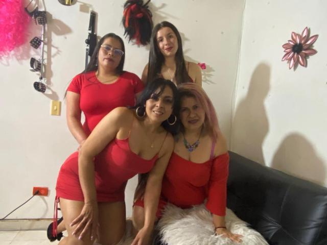 Quatro mulheres do grupo LesbianGrup vestindo vestidos vermelhos, uma com cabelo rosa, uma com cabelo castanho, uma com cabelo preto e uma com óculos, em pé e ajoelhadas, mostrando os seios e o bumbum..