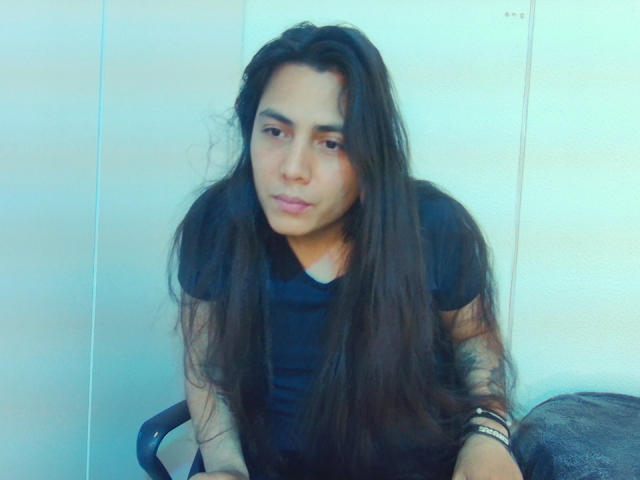 Una mujer llamada Igorendon, con cabello largo y oscuro, vestida con una camisa negra, mirando ligeramente hacia un lado con una expresión neutra, sentada en una silla, imagen con un tono azulado..