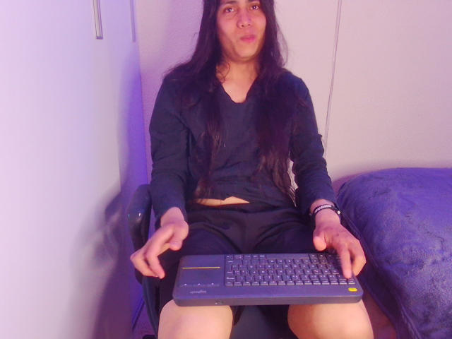 Igorendon, con lunghi capelli neri, indossa una maglietta nera e pantaloncini, è seduto su una sedia con un portatile sulle ginocchia, le mani sulla tastiera, e guarda la telecamera..