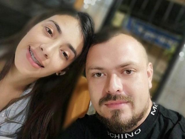 HannaAndHarri are in a selfie, she's smiling with dark hair, he's bald with a beard, wearing a black "CHIND" shirt, both have light skin and brown eyes.