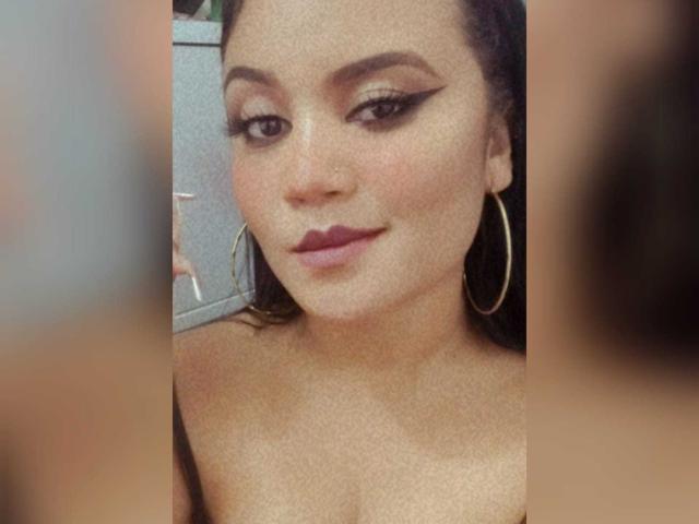 SexyQueenX has dark skin, thick eyebrows, winged eyeliner, hoop earrings, and red lipstick. Her nipples are visible, and she's smiling slightly at the camera.