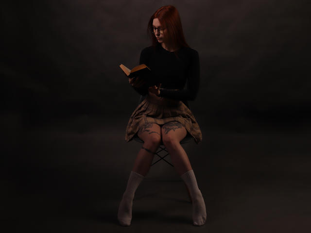 MalenaGolden, avec des cheveux roux, des lunettes, un haut noir et une jupe à carreaux, assise, en train de lire un livre, avec un tatouage sur les cuisses, des chaussettes blanches, dans une pièce sombre, tenant le livre dans sa main droite..