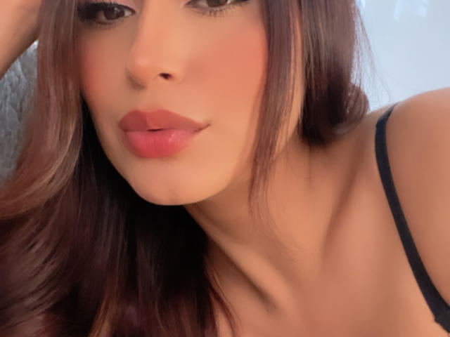 ValeriaKlaus has a cute face with pink lipstick, dark brown wavy hair, and black spaghetti straps. Her brown eyes and slightly parted pink lips are the focus.
