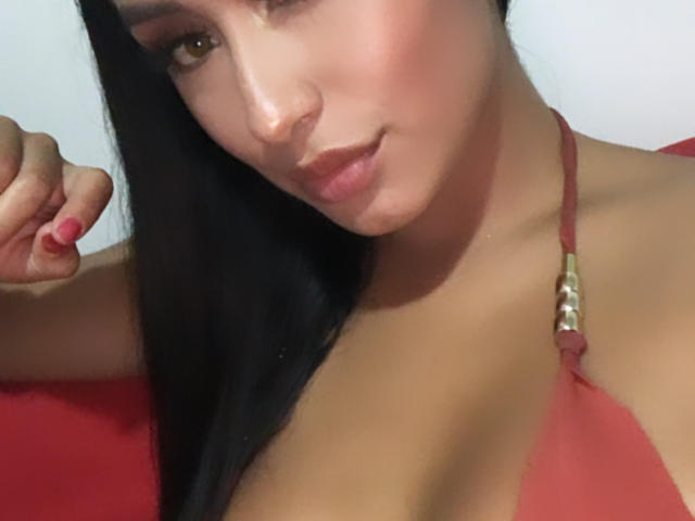 ValeriaKlaus ha la pelle olivastra, lunghi capelli neri, e indossa un top da bikini rosso con anelli dorati, che mette in mostra il seno, e ha lo smalto rosa sulle unghie, con un leggero sorriso..