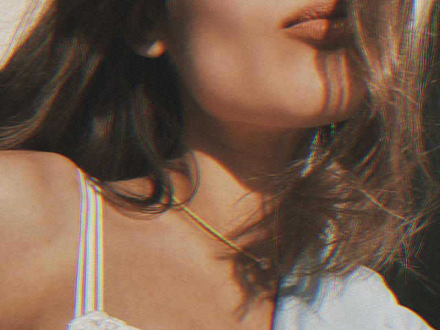 Pingli's face with wavy brown hair, slightly parted lips, and a white tank top with rainbow straps. She's wearing a thin necklace, and her skin is sunlit.