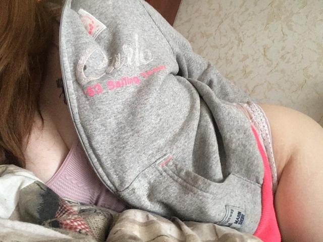 Rubbi's grey hoodie is pulled up, exposing pink underwear and her ass. Her pink tank top and lace underwear are visible. Her brown hair is partially shown.