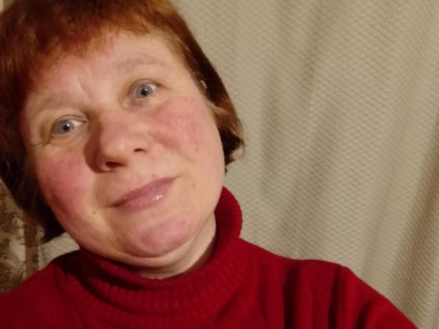 Jack, con i capelli rossi, la pelle chiara e gli occhi azzurri, indossa un maglione a collo alto rosso, ha un leggero sorriso e qualche lentiggine, e guarda leggermente di lato..