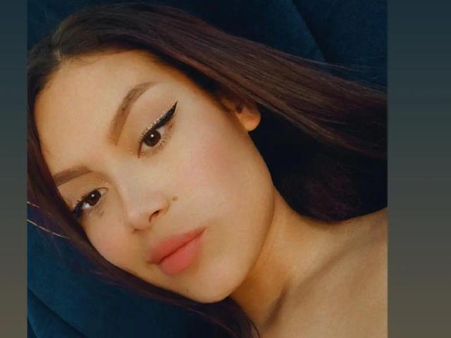 MalejaI heeft een lichtbruine huid, lang bruin haar, een eyeliner met een vleugje en roze lippen. Ze kijkt iets naar links en heeft een klein beauty markje op haar rechterwang..