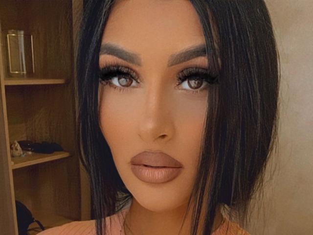 SelenaCruz tem cabelo castanho escuro, sobrancelhas grossas, cílios longos, olhos castanhos e lábios cheios, de cor natural. Seu rosto está centralizado, olhando diretamente para a câmera..