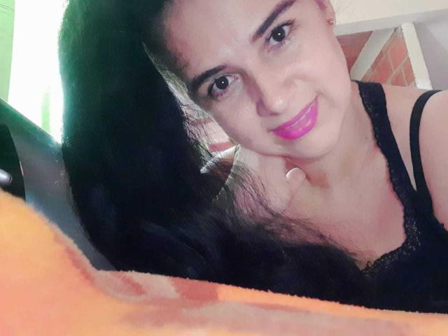 Brihana Charlot ha lunghi capelli neri, rossetto rosa e un sorriso adorabile, indossa una maglia nera in pizzo e, in un selfie, appoggia il mento sulla mano..