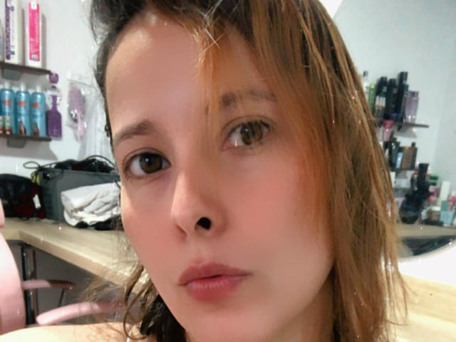 SaritaVelez's face, with wet brown hair, brown eyes, and pinkish lips, staring into the camera with a neutral expression. Her nose is small and her skin is fair.