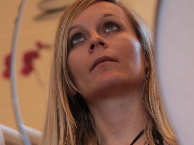 SharoneRey has blonde hair, blue eyes, and a slightly upturned face with a neutral expression. Her nose is centered, and she's looking upwards with a slight gaze.