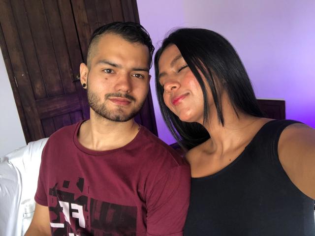 BradAndJenn, een man met een bruine huid, een baard en oor piercings, gekleed in een donkerrode shirt, staat naast Jenn, een vrouw met een getinte huid en zwart haar, in een zwarte tanktop..