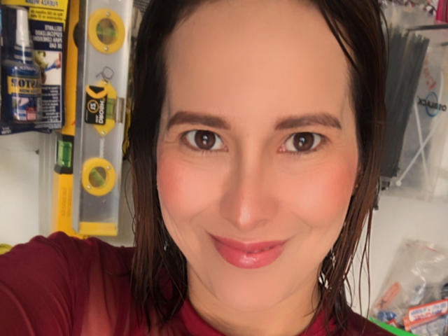 SaritaVelez has wet brown hair, brown eyes, pink lipstick, and a slight smile, wearing a red shirt, with a clean, slightly flushed face and a cute, sexy look.
