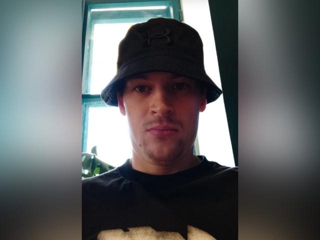 JonnyXTower, wearing a black Under Armour bucket hat, has a slight beard and is looking at the camera with a neutral expression, wearing a black shirt.