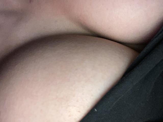 Les seins volumineux, pâles et nus de JujuBeuty sont pressés l'un contre l'autre, révélant une peau douce et une légère teinte rosée, partiellement recouverts de tissu noir sur le côté droit de l'image..