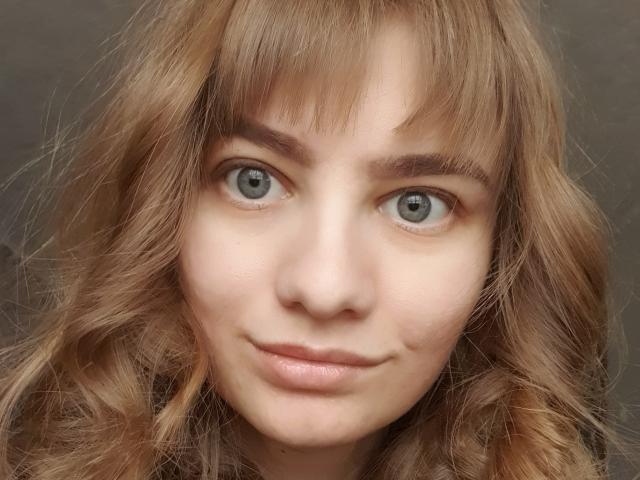 LinNatty hat eine helle Haut, grüne Augen und welliges, hellbraunes Haar mit Pony. Sie lächelt sanft mit rosafarbenen Lippen. Ihre Augenbrauen sind dunkel und leicht buschig..