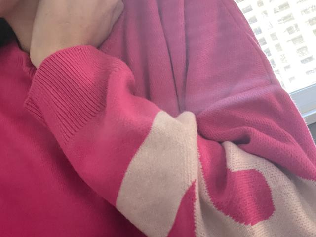 Le pull rayé rose et blanc de RozalinaPleasure, avec une main touchant sa poitrine, met en valeur son tissu doux et moelleux ainsi que sa texture agréable. Ses seins sont légèrement visibles..