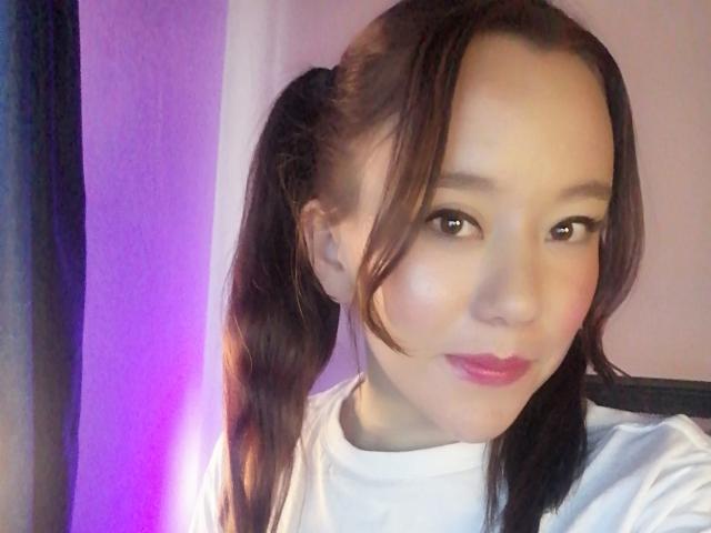 TamyParist heeft vlechtjes, een lichte huid, bruine ogen, roze lippenstift en draagt een witte blouse. Haar borsten zijn niet zichtbaar. Ze glimlacht lichtjes en heeft een schattig gezicht..