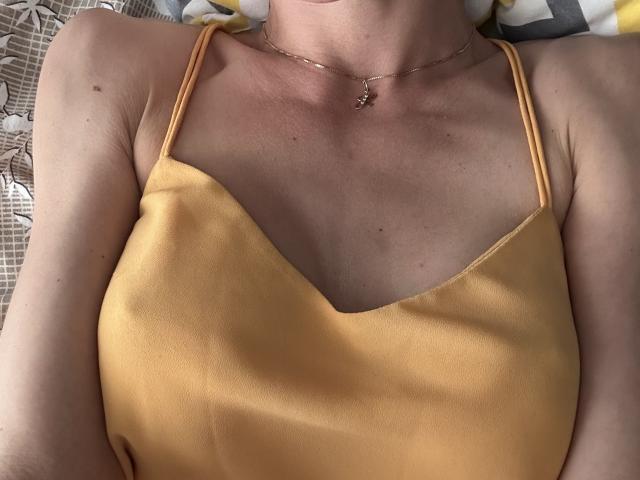 BellaJulls' chest in a yellow camisole with thin straps, showing her small tits and light skin. She's wearing a delicate necklace with a small pendant.