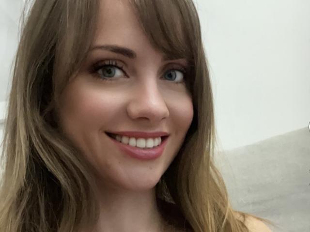 SammyPeeks tiene el cabello rubio y ondulado, ojos azules y una sonrisa encantadora con lápiz labial rosa. Su nariz es pequeña y su piel es clara. Está mirando ligeramente hacia la derecha..