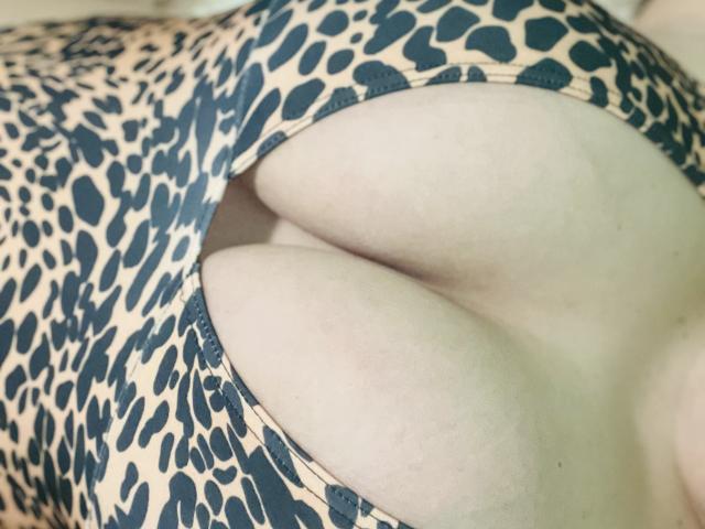 Barbarica's large, pale tits are pushed up by a leopard-print, cutout, one-piece. The fabric clings to her chest, showing her ample cleavage and smooth skin.