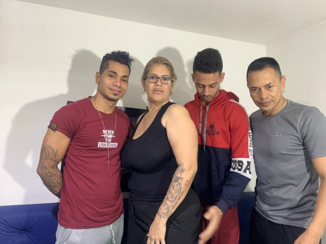 Quattro ragazze, in piedi insieme: una con i capelli ricci e scuri e tatuaggi, vestita con una maglietta rossa; una con i capelli biondi e gli occhiali, con un top nero; e altre due con i capelli corti..