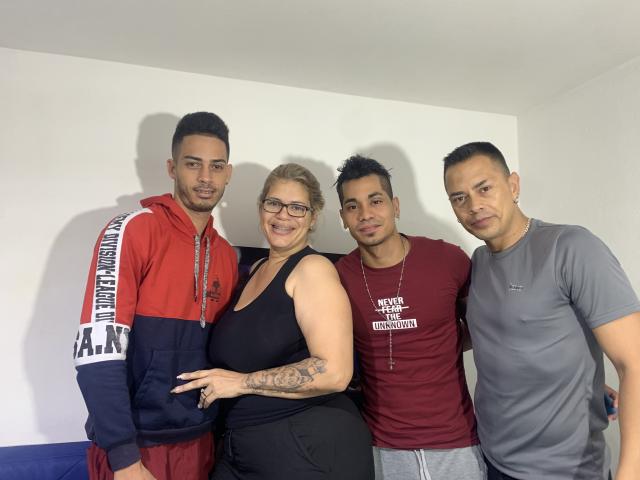 Four HottestFoursome stand together. The guy on the left wears a red hoodie with "ANK" on the sleeve, the woman in the center has big tits and glasses, the guy on the right wears a maroon shirt, and the guy on the far right wears a gray tee.