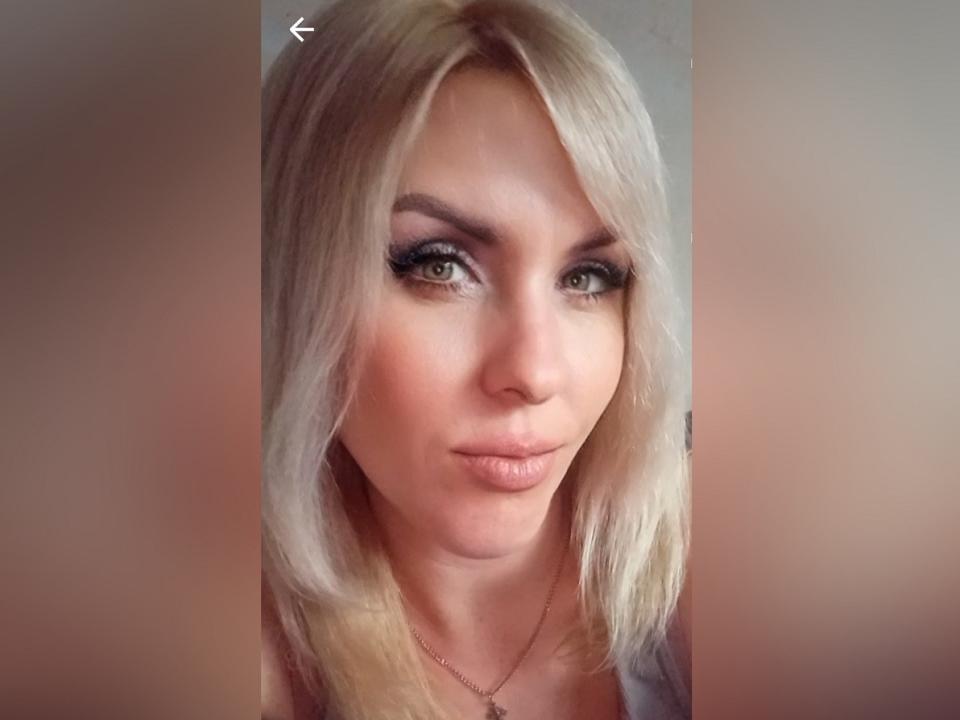 A loira Alisa, com lábios carnudos, olhos verdes e delineador marcante, veste uma blusa rosa, tem um rosto bonito e está fazendo uma carinha de beijo. Seus seios são pequenos..