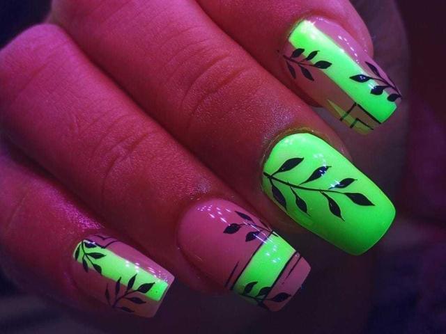 Le unghie di HannaSofis sono di un verde neon brillante, con motivi a foglie nere sulle punte rosa, che mettono in risalto le sue dita lucide e curate. Il seno non è visibile..