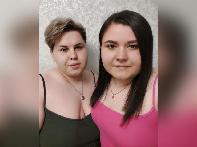 BeckyAndEllen con i capelli castani corti e una maglietta verde, e BeckyAndEllen con i capelli neri lunghi e una maglietta rosa, entrambe che mostrano il loro seno prosperoso..