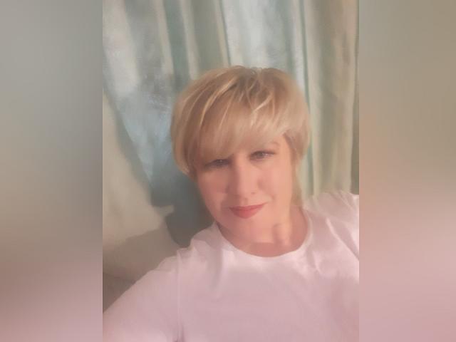 Andrea Tay tiene el cabello rubio corto, piel clara y lleva una camisa blanca con una sonrisa sutil. Sus labios rosados están ligeramente entreabiertos. La foto es suave y ligeramente borrosa..