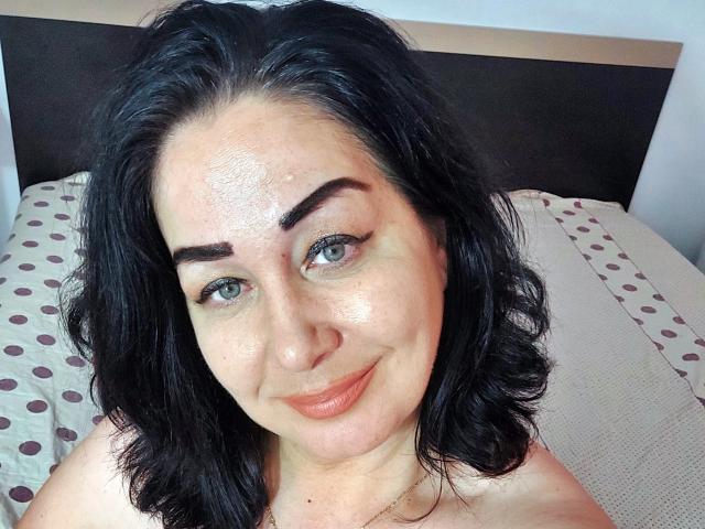 LexyRose tiene una piel brillante, cabello negro ondulado y una ligera sonrisa, con ojos azules, y se muestra en un selfie, sin ropa, exhibiendo sus pechos..
