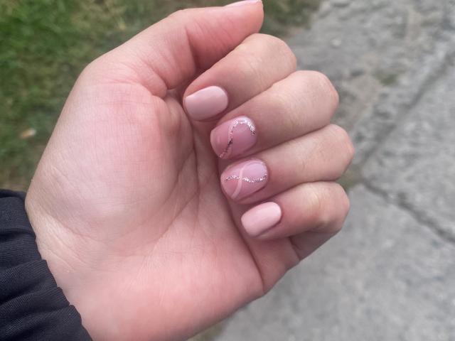 La main de ShannelTaylor, avec ses ongles roses, chacun orné d'un petit cœur scintillant près de la cuticule, présente des doigts fins, légèrement courbés, d'une douceur rose, et une peau claire et délicate..