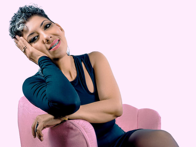 A digital art piece with a minimalist style. A large, abstract, pink and black symbol is centered. The symbol has a black dot in the top left. Simple, clean lines.