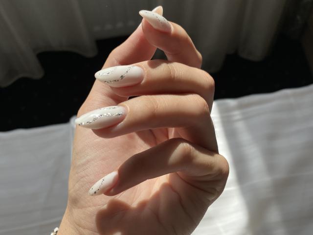 Graphic with a large, stylized letter "L" in the center, colored in soft pink and white. The "L" is bold with smooth, curved lines and a subtle shadow.