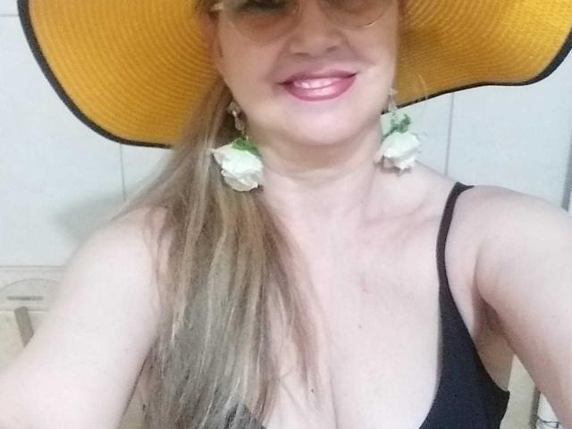 LadyMariahX with yellow sunhat, black strap top, pink lipstick, white flower earrings, long blonde hair, smiling, showing tits, wearing sunglasses, fair skin, cute, sexy, photo.