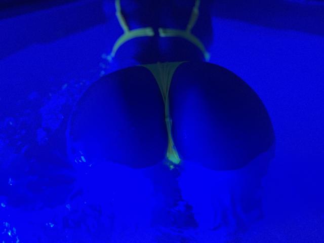 CristalHotty69's ass in a yellow thong, submerged in blue-lit water, viewed from behind, with visible buttocks and thong straps.