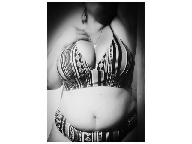 JuliaFrancaise vestida con un bikini a rayas, con senos grandes, manos cerca del cuello, foto en blanco y negro, ombligo visible, luz suave, ligera sombra, de pie, parte superior del cuerpo, tejido texturizado, pose casual..