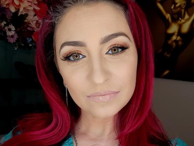 Agaa heeft felrood haar, bruine ogen met dikke wimpers en glanzende, roze lippen. Ze draagt een turquoise top met een zilveren oorbel. Haar make-up is perfect aangebracht..