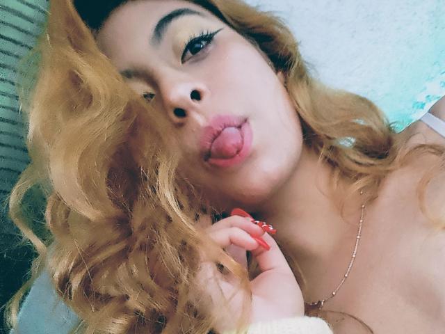 Samantha Smith, con i capelli biondi mossi, la lingua di fuori e i puntini neri sul naso, ha le unghie rosse e una collana d'oro, appare sexy in un selfie..