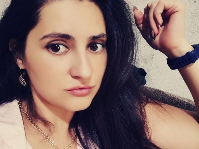 JennaEasy ha i capelli scuri e ondulati, gli occhi marroni e il rossetto rosa. Indossa una catena d'oro, degli orecchini e un braccialetto blu, e appare seria con il braccio alzato..