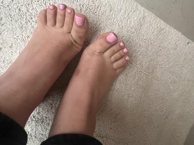 Les pieds de Barbarica, avec des ongles peints en rose, des semelles légèrement sales et une petite ecchymose sur le gros orteil droit, reposent sur une serviette blanche texturée..