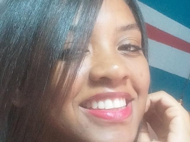 TiffanySammy, con cabello negro brillante, guiñando un ojo, sonriendo con lápiz labial rosa, mostrando dientes blancos, tocándose la barbilla, primer plano, ligeramente borroso, luciendo linda y sexy..