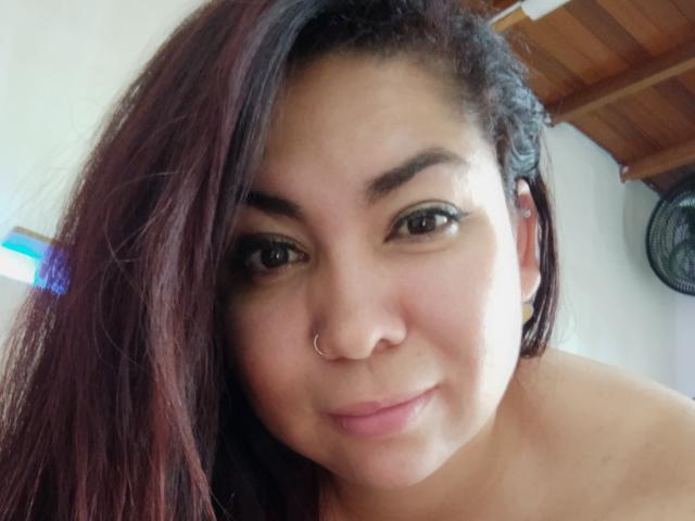 KathyMichels ha gli occhi marrone scuro, un piccolo piercing al naso e lunghi capelli marrone scuro, leggermente ondulati. Sorride dolcemente, mostrando un rossetto rosa chiaro. La sua pelle è marrone chiaro..