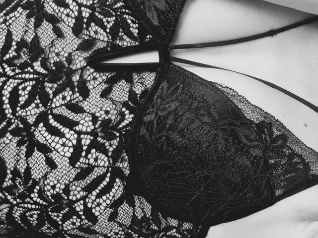 ApoloniaRed's black lace bra with floral patterns, showing her tits through the sheer fabric, straps crossing her chest. Black and white, textured lace, seductive, intimate.